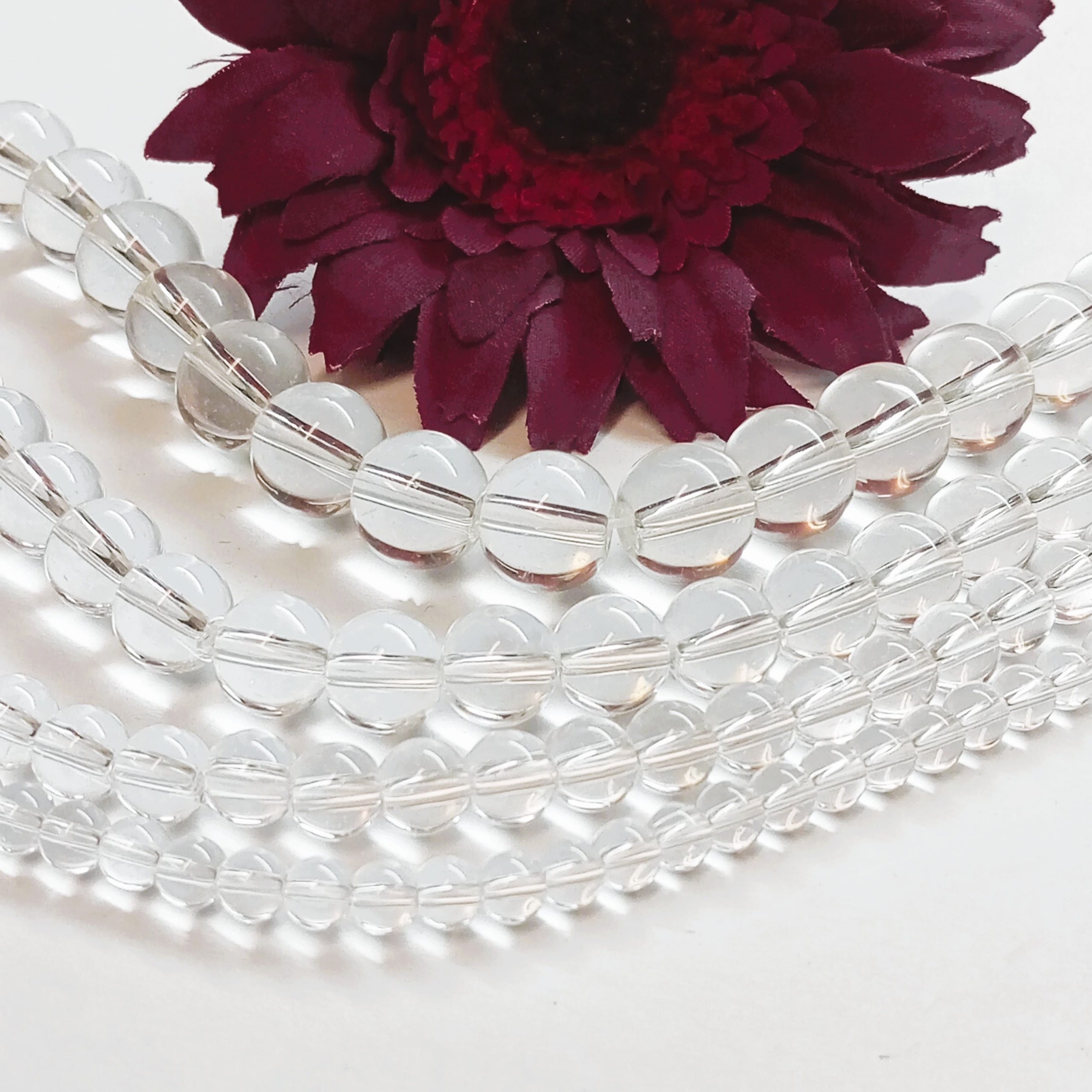 assortiment de perles en quartz cristal de roche tailles 4mm 6mm 8mm 10mm sur support blanc pour création DIY