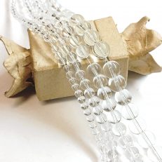 assortiment de perles en quartz cristal de roche tailles 4mm 6mm 8mm 10mm sur support blanc pour création DIY